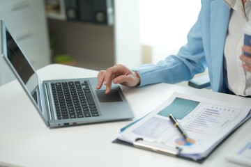 Asian and African businesswoman using laptop and drinking coffee in modern office