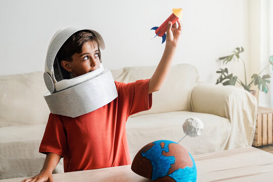 Astronaut child dreams of travel in space with crafty rocket ship at home - Happy boy playing and exploring galaxy