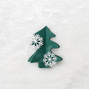 Decorative Christmas tree from green craft paper, Christmas and New Year holiday composition. Handmade fir decorated snowflakes on white fur background. Top view, flat lay, Winter holidays card