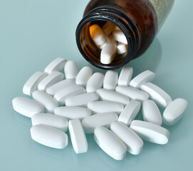 White large pills and glass bottle on a blue background