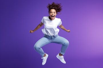 Cheerful Young Woman Jumping in Vivid Violet Studio