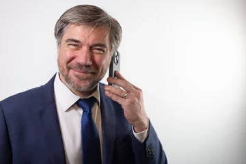 Fototapeten homme d'affaires, patron d'entreprise de 45 ou 50 ans qui téléphone avec un smartphone. Symbole de réussite professionnelle. Sur fond blanc. © Tof - Photographie