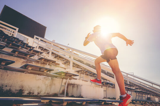 Young man running sprinting up stairs at stadium. Fit runner fitness runner during outdoor workout. Selected focus