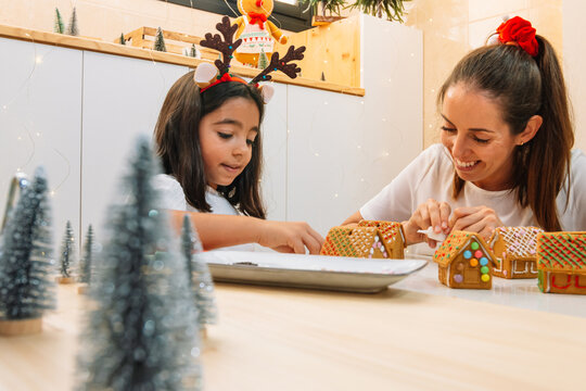 Mother and daughter laugh as they put the finishing touches on the gingerbread cookies for Christmas.dng