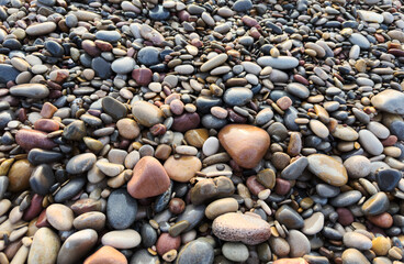 Pebble stones close-up. Stone beach background. Coastline pebbles beach. Stones on beach. Decorative texture of stones. Sea stones background. Colored stone on coastline. Stone background, texture.