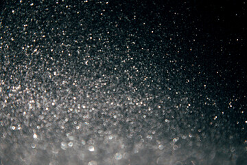 Shining sparkling black blurred background for holiday design. Christmas abstract sparkles, selective focus
