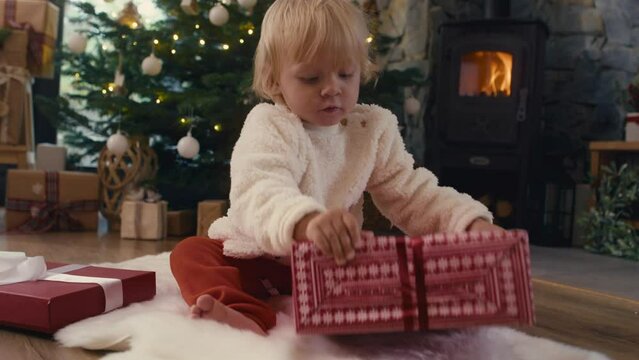 Caucasian toddler unpacking Christmas present. Shot with RED helium camera in 8K.   