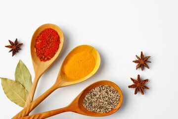 Spice in wooden spoons on white background