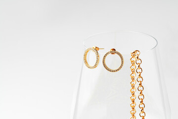 Wine glass and golden jewelry inside on white background