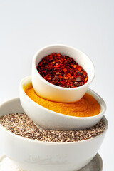 Bowls with spices and cooking ingredients on white background