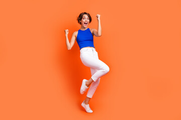 Full size portrait of funky overjoyed girl raise fists shout yes hooray accomplishment isolated on orange color background