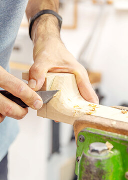 vertical shot of a luthier carving the neck . Carpentry workshop.