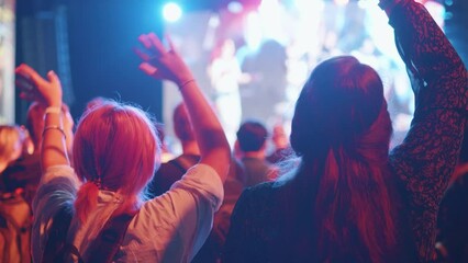 Girls waving hands at music anime cosplay gaming convention concert.