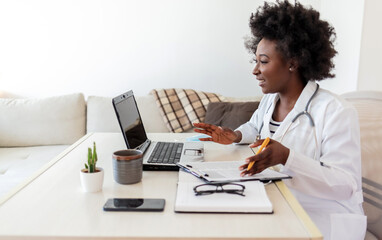 African American woman doctor working at her office doing telemedicine services. Helping patients...