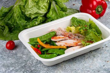 Turkey filet with fresh vegetables. Healthy diet. Takeaway food. Eco packaging. On a wooden background.
