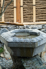 Close up shot of purification fountain with bamboo and wooden scoop in Japan