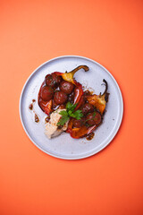 A hearty lunch of peppers stuffed with tomatoes on an orange background.
