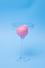 A scoop of ice cream in a beautiful glass bowl on a colored background.