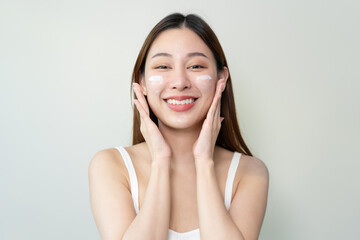 wellness care concept,  young woman looking at the mirror and applying facial skin care cream on her face