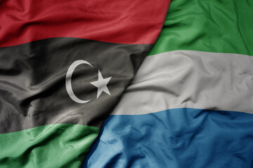 big waving national colorful flag of libya and national flag of sierra leone .