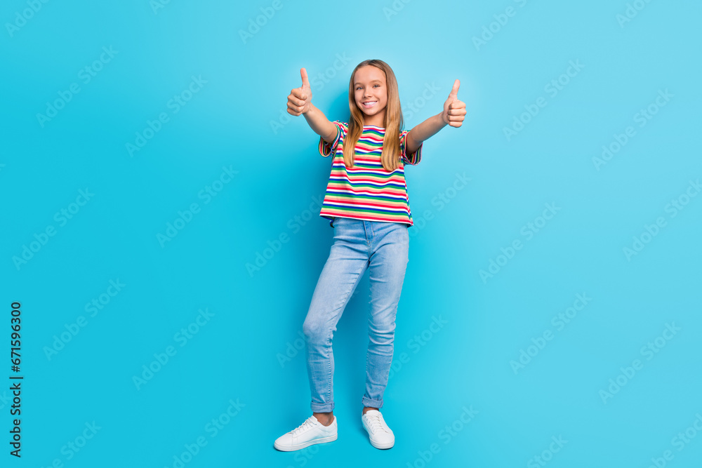 Wall mural Full length photo of good mood schoolgirl dressed striped t-shirt jeans showing thumbs up to you isolated on blue color background