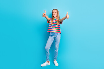 Full length photo of good mood schoolgirl dressed striped t-shirt jeans showing thumbs up to you isolated on blue color background