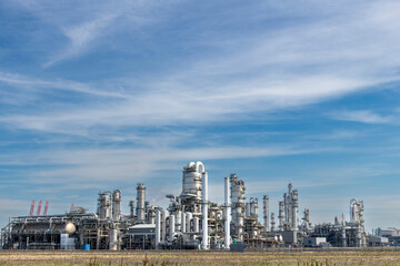 Fototapeta na wymiar Panoramic view of a chemical plant or refinery with fractioning or distillation towers, boilers and pipes for oil and chemicals against a blue sky