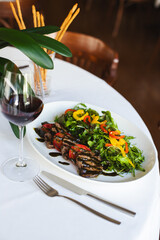 Veal medallions with a portion of salad on a beautiful white plate. Restaurant serving of food. Food photo.