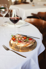 Appetizing bruschetta with thin pieces of meat and tomatoes on a light background. Food photography.