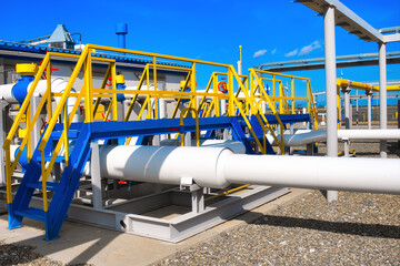 Gas station. Industrial facility for transportation and processing of natural gas. Metal stairs and passages over pipes on territory of gas distribution station. View on summer day.