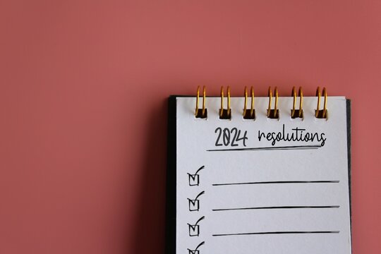 Top view image of notebook with text 2024 RESOLUTIONS. Copy space for text. New years resolutions concept