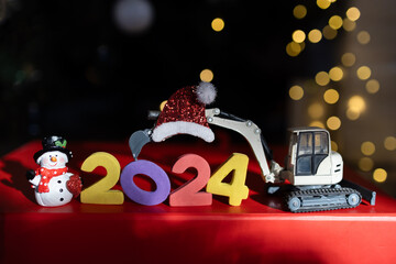 multi-colored numbers 2024, toy mini excavator, souvenir snowman, bokeh. Christmas holidays,...
