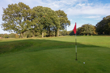 Golf green with ball and red flag on Chorleywood Common, Hertfordshire