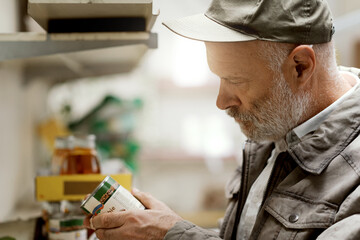 Old man buying canned food at the supermarket