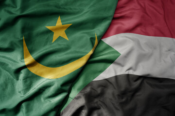 big waving national colorful flag of mauritania and national flag of sudan .