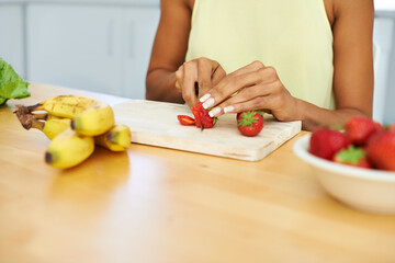 Woman, hands and cutting strawberry in kitchen for diet, healthy meal or fruit salad at home. Closeup of female person or vegetarian slicing organic red fruits for natural nutrition, vitamin or fiber