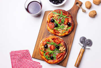 Two pizzas with mozzarella cheese, nuts, arugula, tomatoes and olives. Italian food. Vegetarian food.
