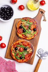 Two pizzas with mozzarella cheese, nuts, arugula, tomatoes and olives. Italian food. Vegetarian food.