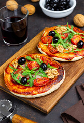 Two pizzas with mozzarella cheese, nuts, arugula, tomatoes and olives. Italian food. Vegetarian food.