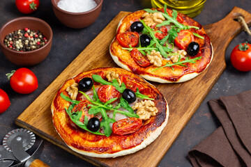 Two pizzas with mozzarella cheese, nuts, arugula, tomatoes and olives. Italian food. Vegetarian...