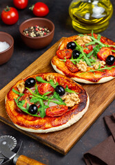 Two pizzas with mozzarella cheese, nuts, arugula, tomatoes and olives. Italian food. Vegetarian food.