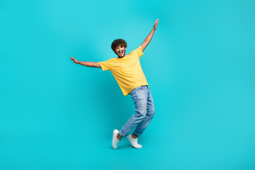 Fototapeta na wymiar Full length photo of nice young male dancing tiptoes have fun wear trendy striped yellow garment isolated on aquamarine color background