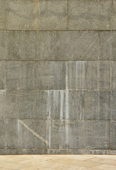 The texture of a wall of large granite tiles that are covered with white streaks when exposed to...