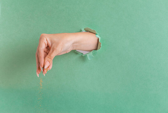 a woman's hand pours a magical golden powder on a green background. Christmas card