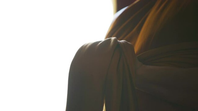 monk uses his hands to hold his robes to get dressed