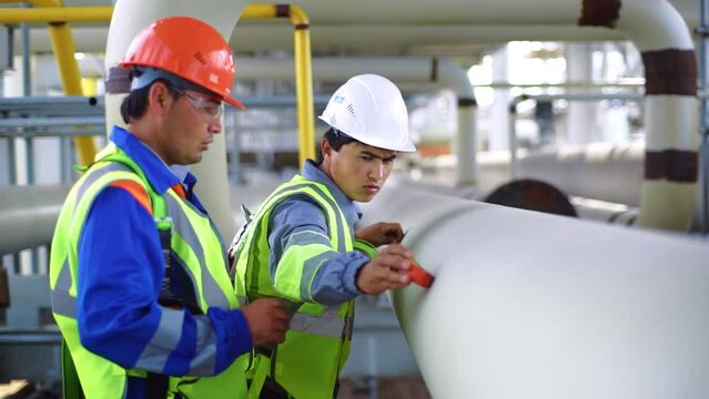 Two man industrial builder engineer in uniform measuring pipe size for refinery construction rig