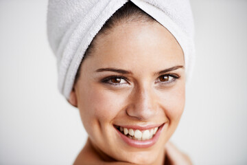 Smile, beauty and woman with towel in a studio for health, wellness and natural face routine. Happy, skincare and portrait of young female model with facial dermatology treatment by gray background.