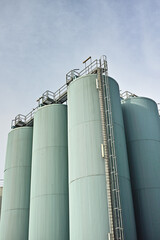 Silo storage tankers against a gray sky in Danish oil industry. large oil plant storage tanks for export in industrial area. Silo tankers for keeping bulk food products, substances and materials safe