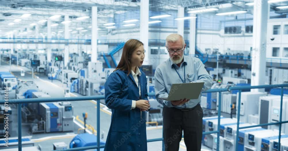 Poster multiethnic male and female colleagues standing in a manufacturing complex, using laptop computer an