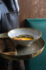 Pumpkin puree soup on a waiter's tray. Presentation of the autumn menu
